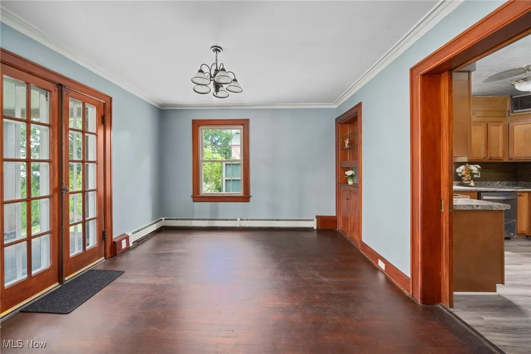 Unfurnished dining area with wood finished floors, a chandelier, and ornamental molding