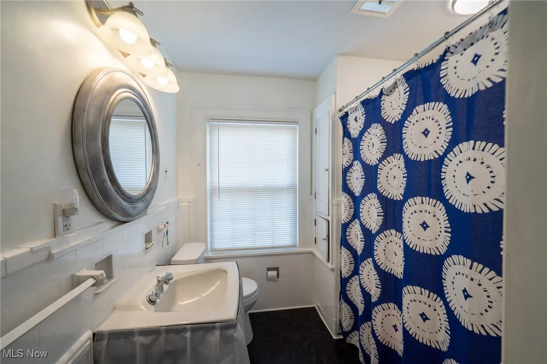 Bathroom featuring curtained shower and a wainscoted wall