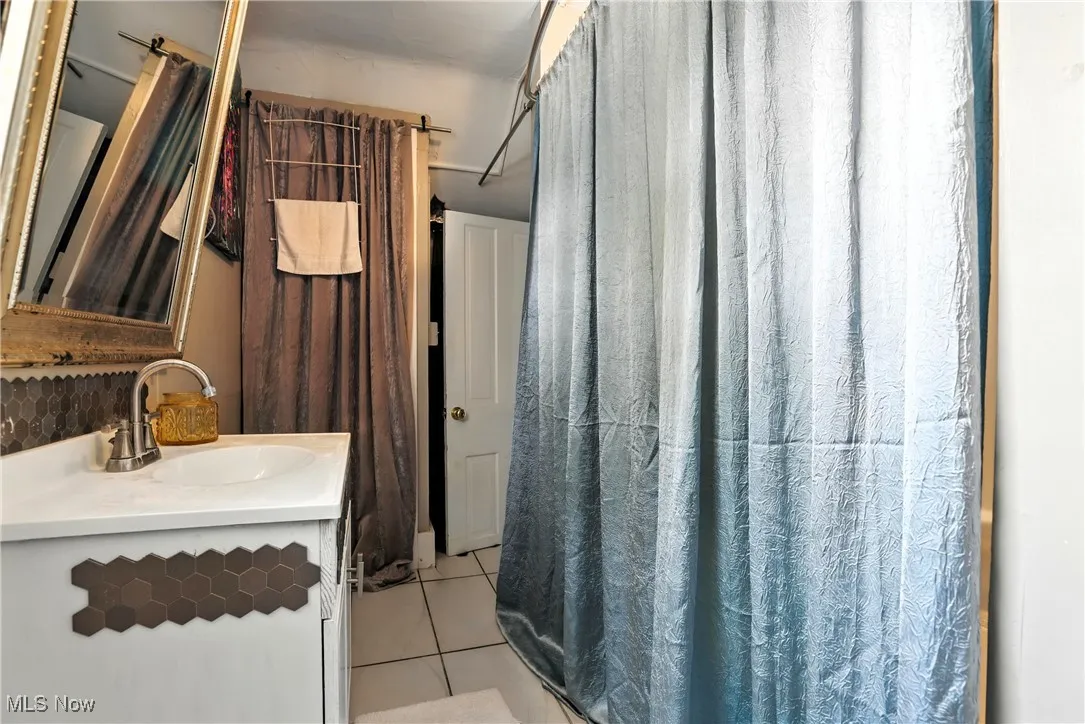 Full bath with vanity, tile patterned floors, and a shower with shower curtain