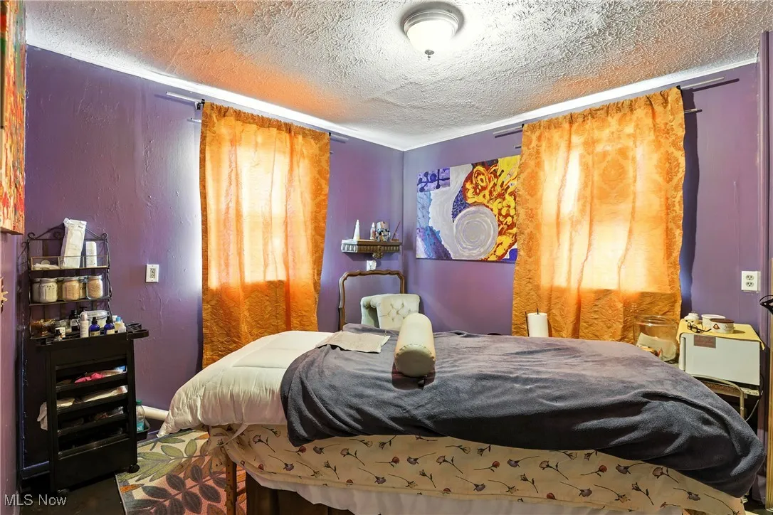 Bedroom featuring a textured ceiling and a textured wall
