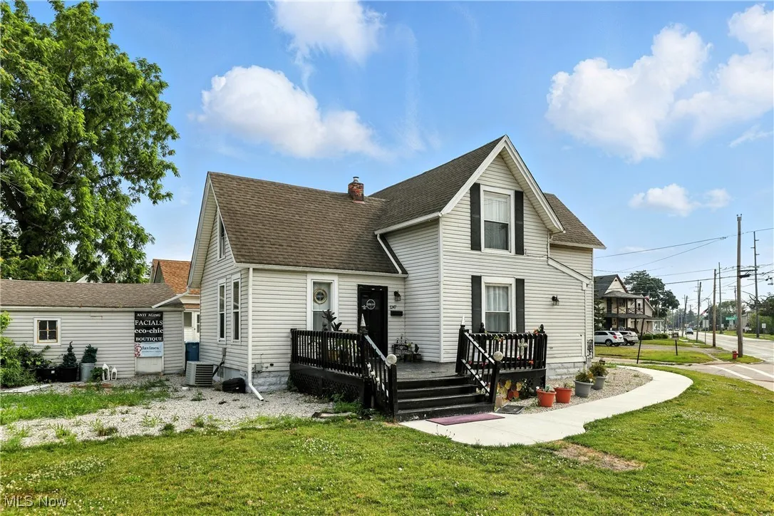 Rear view of house with a yard, a deck, and roof with shingles