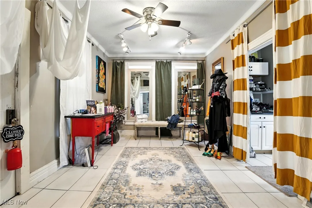 Miscellaneous room with track lighting, ceiling fan, and light tile patterned floors