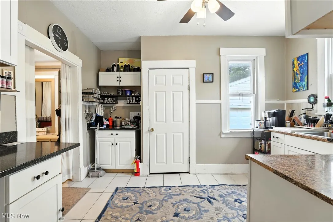 Kitchen with ceiling fan, light tile patterned flooring, and white cabinetry