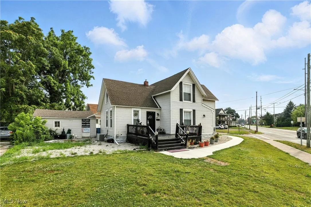 Back of property with a lawn, a deck, a chimney, and a shingled roof