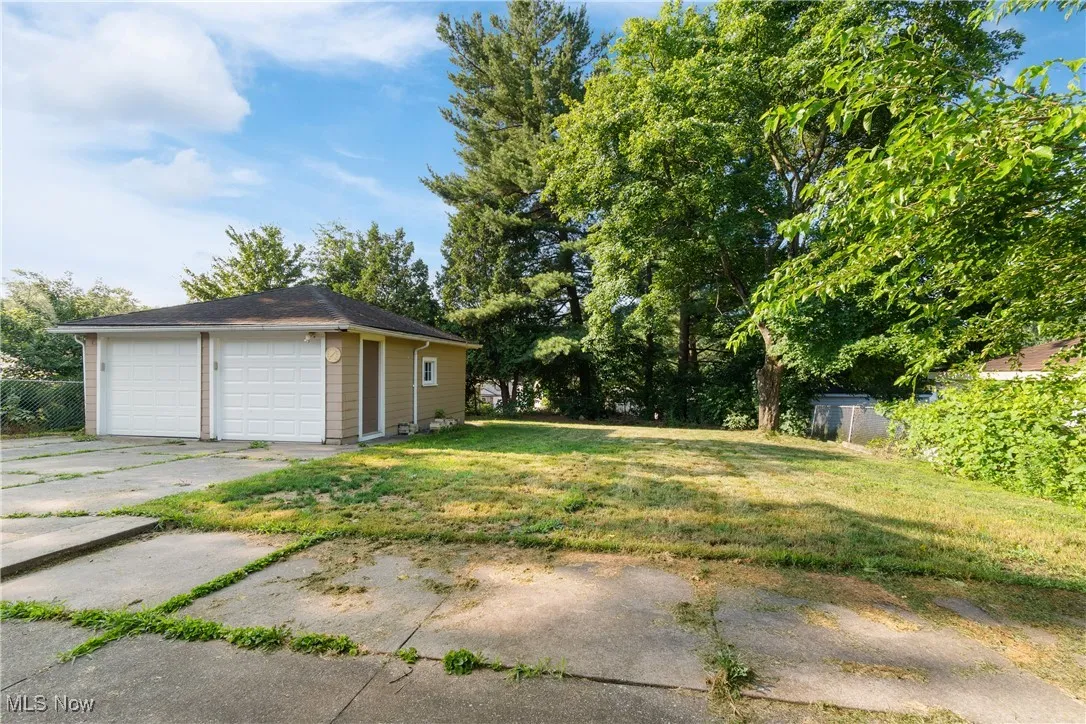 View of grassy yard featuring a detached garage and an outbuilding