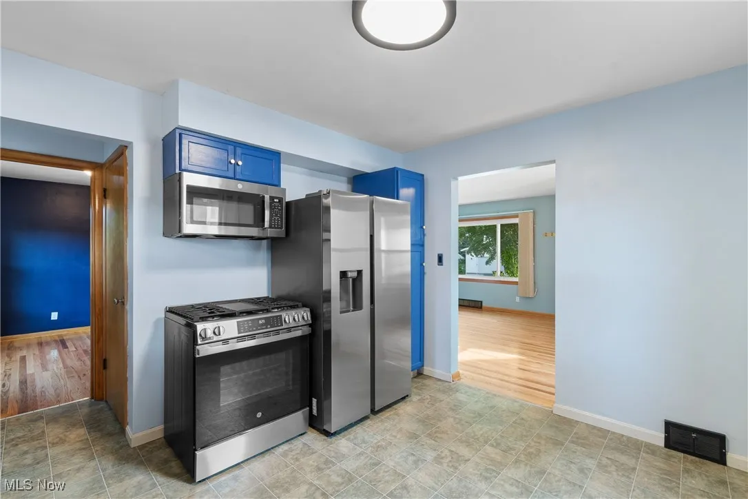 Kitchen with appliances with stainless steel finishes and blue cabinetry