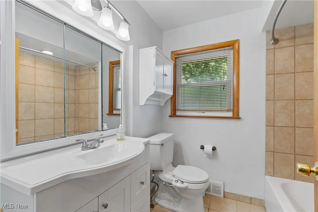 Bathroom featuring vanity, tile patterned floors, and washtub / shower combination