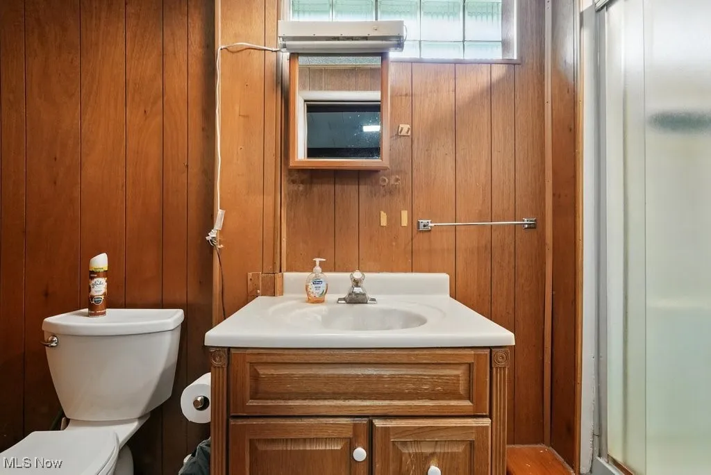 Full bathroom featuring vanity, a shower stall, and wooden walls