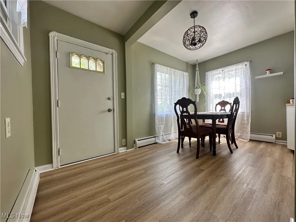 Dining space with baseboard heating, a chandelier, and light wood finished floors