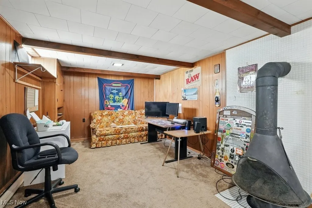 Office featuring beam ceiling, carpet, and wood walls