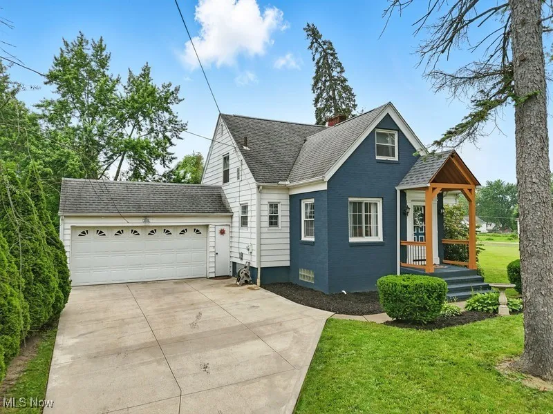 View of front of property with driveway, an attached garage, a front yard, a chimney, and roof with shingles