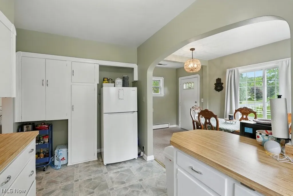 Kitchen featuring freestanding refrigerator, arched walkways, a baseboard heating unit, and healthy amount of natural light