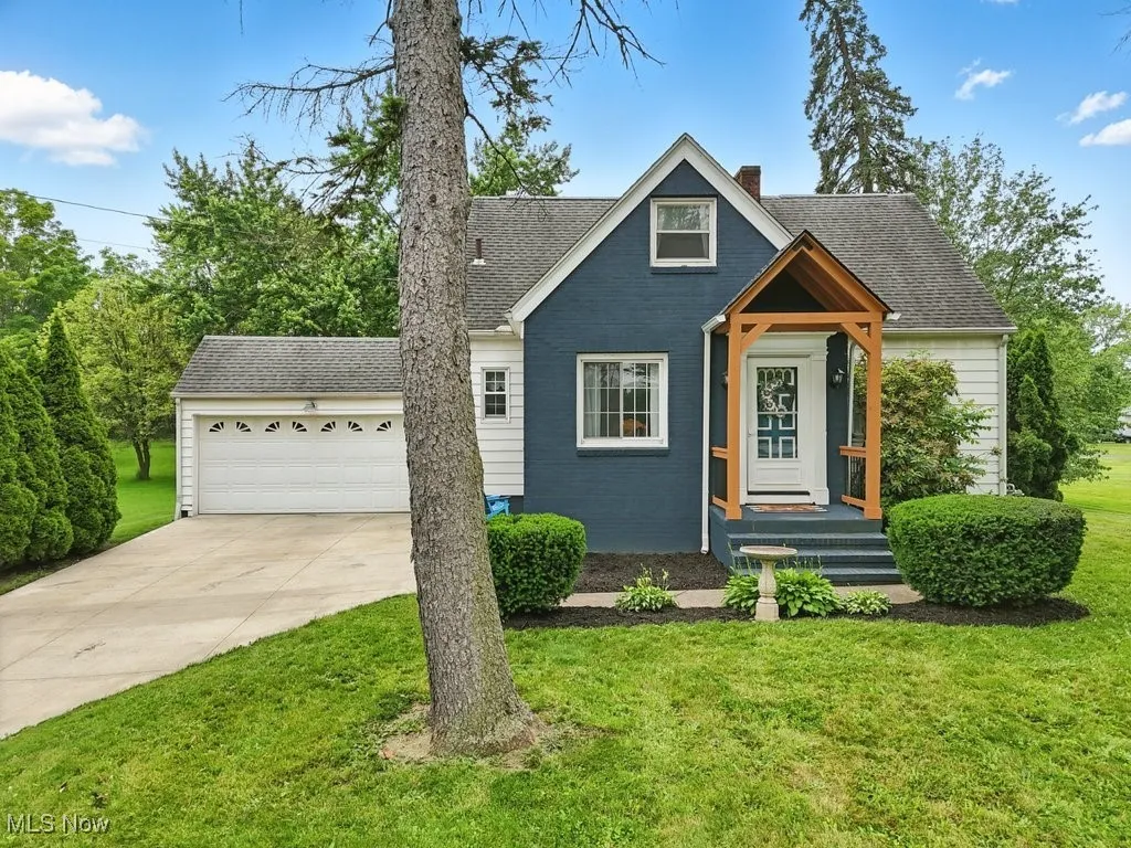 View of front of house featuring concrete driveway, a front lawn, a shingled roof, and an attached garage