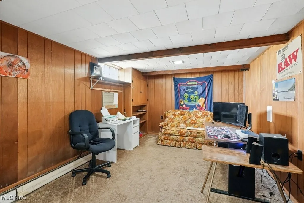 Office space featuring wood walls, light colored carpet, and beamed ceiling