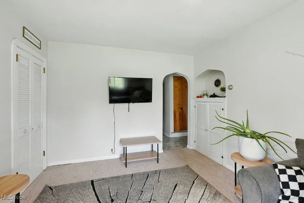 Carpeted living area with arched walkways and baseboards