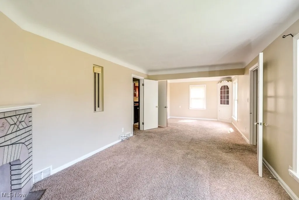 Empty room with a fireplace and light carpet