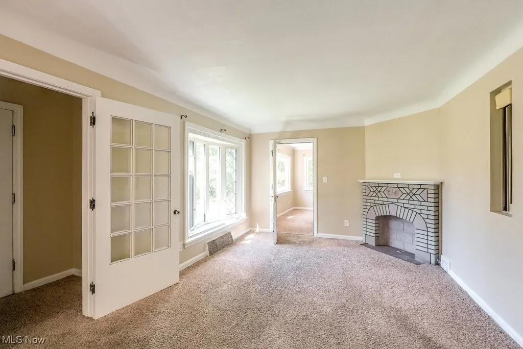 Unfurnished living room featuring carpet and a brick fireplace