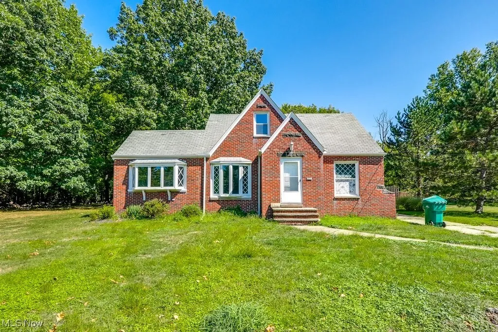 View of front of home featuring brick siding, entry steps, a front lawn, and a shingled roof
