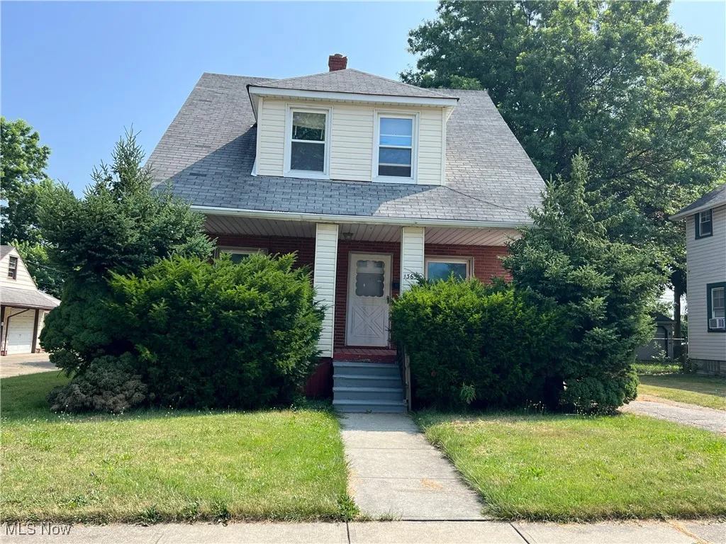View of front of house with a front yard, a porch, and a shingled roof