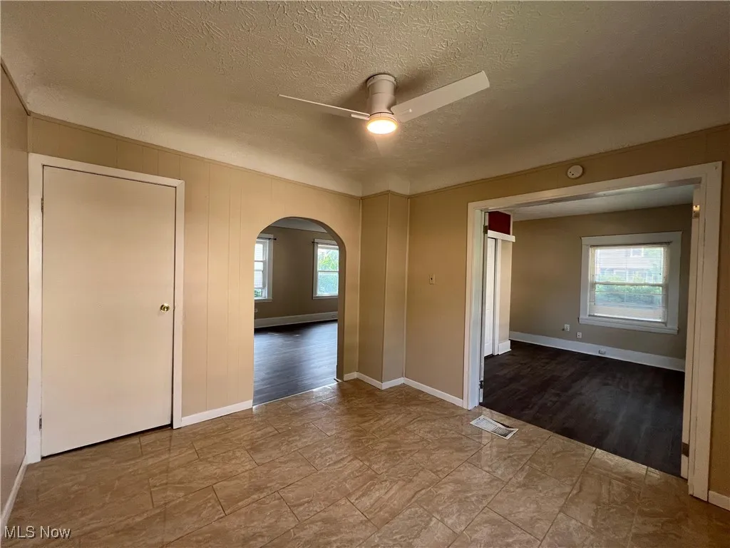Unfurnished room featuring a ceiling fan, arched walkways, and a textured ceiling