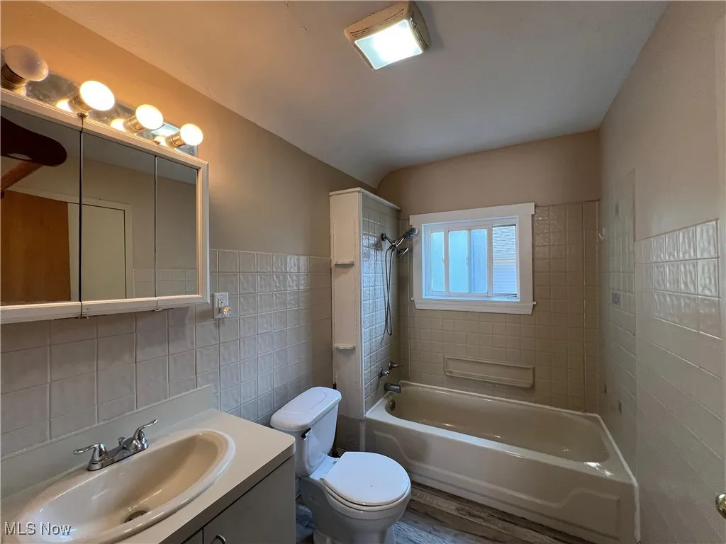 Full bath featuring tile walls, bathtub / shower combination, and vanity