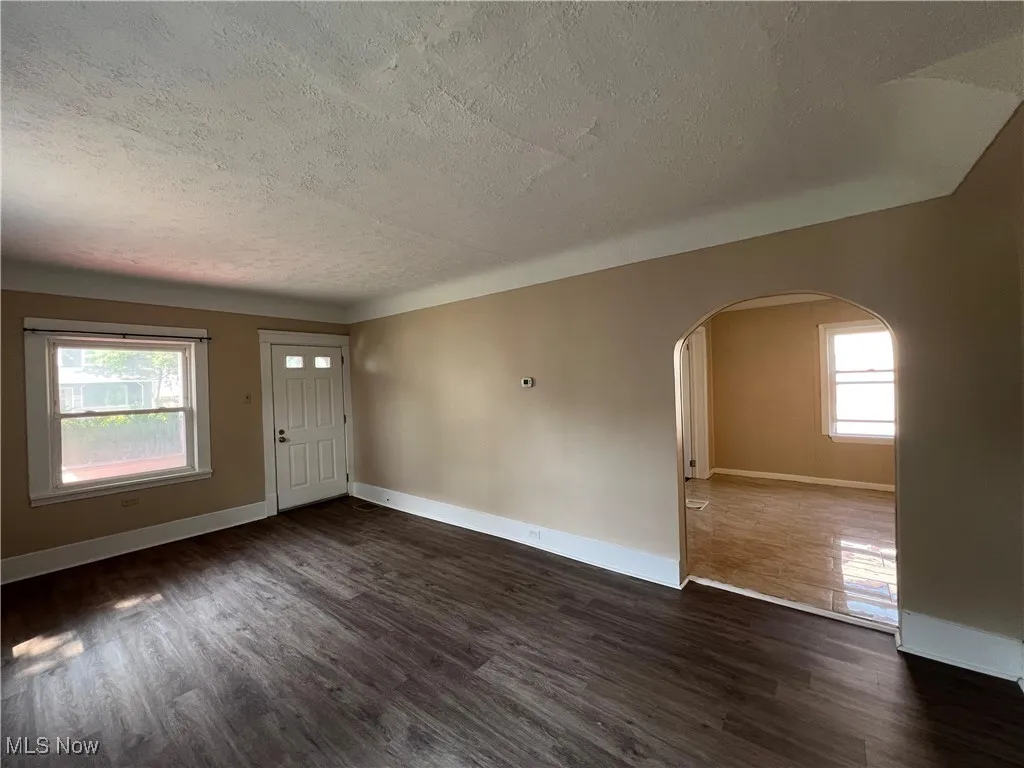 Entryway featuring arched walkways, a textured ceiling, and dark wood-type​​‌​​​​‌​​‌‌​‌‌​​​‌‌​‌​‌​‌​​​‌​​ flooring