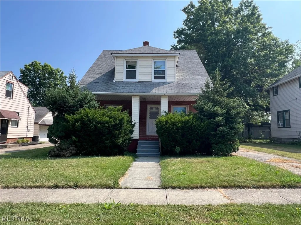 Bungalow-style home featuring a front lawn, covered porch, and a shingled roof