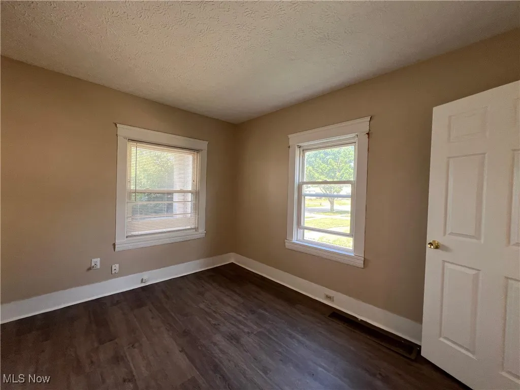 Empty room featuring dark wood-style flooring and a textured ceiling