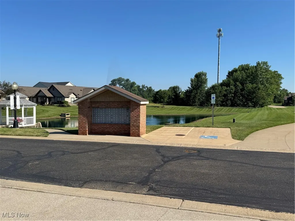 View of front facade featuring a water view, a gazebo, brick siding, and a front yard