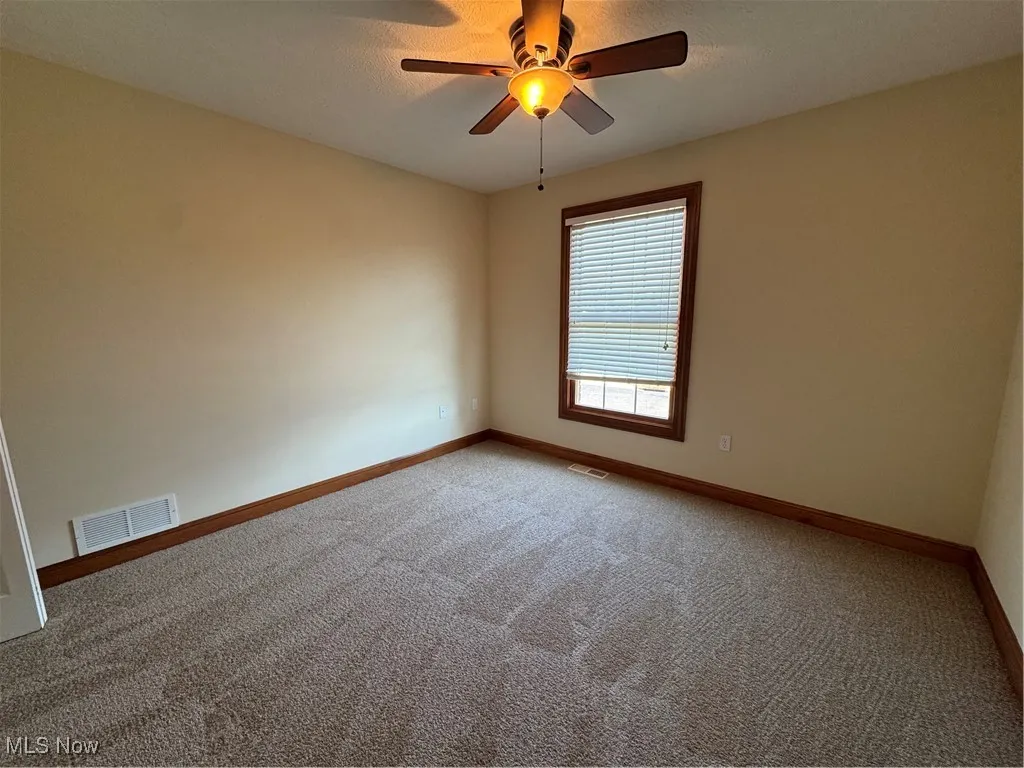 Carpeted empty room featuring baseboards and ceiling fan
