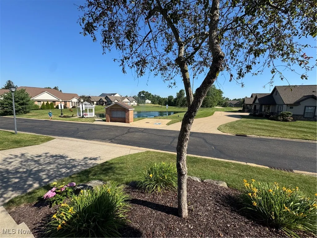 View of asphalt road featuring a water view, street lights, and a residential view