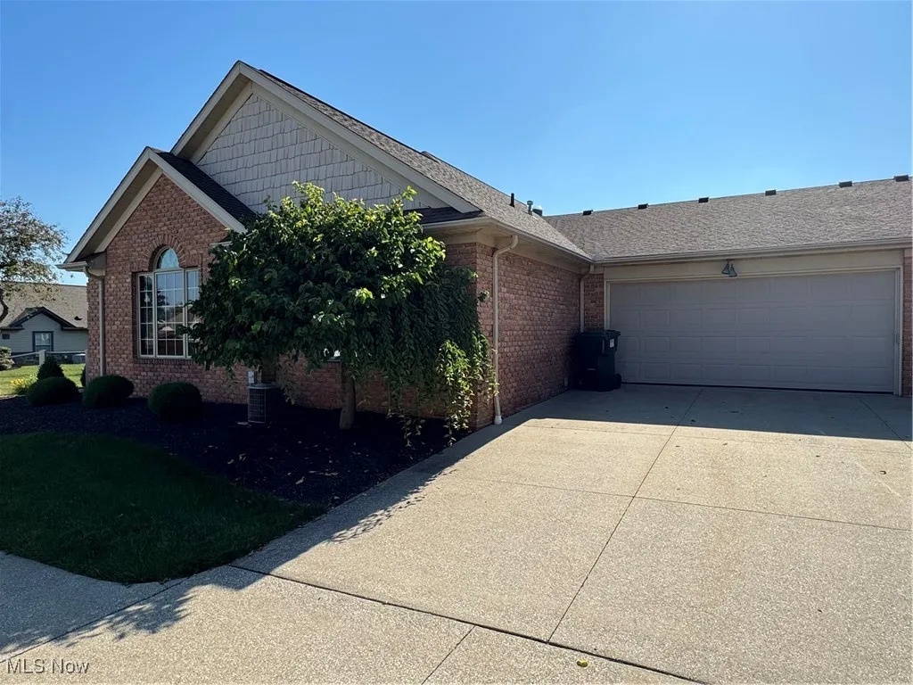 View of front of house featuring brick siding, concrete driveway, and an attached garage