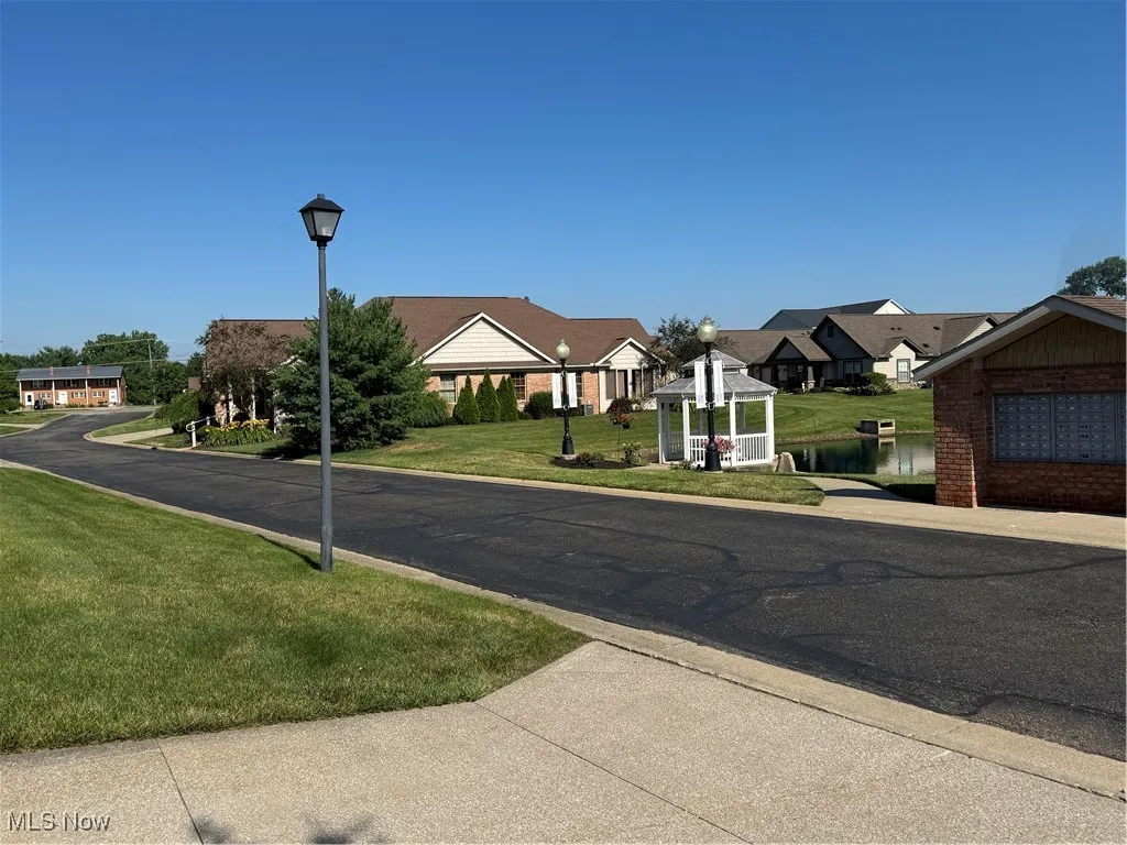 View of asphalt road featuring street lights, a residential view, and curbs