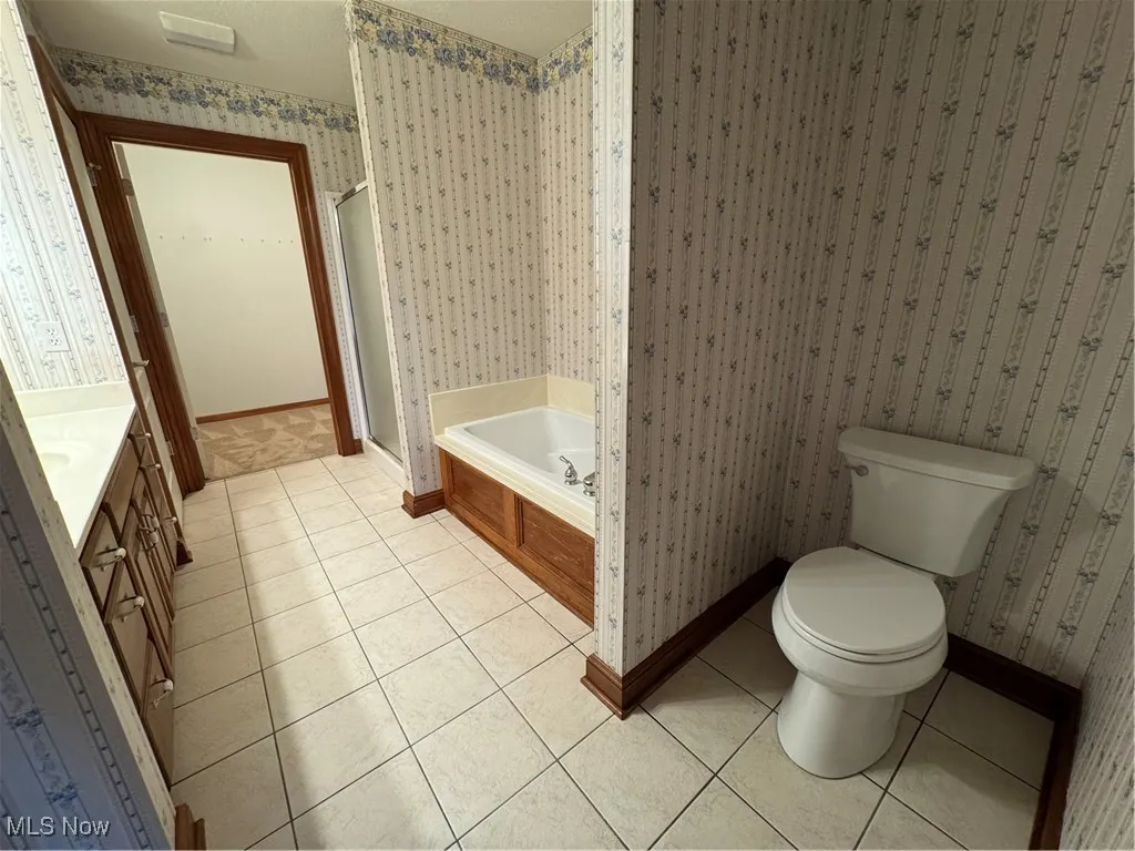 Bathroom featuring tile patterned flooring, a garden tub, wallpapered walls, a stall shower, and vanity