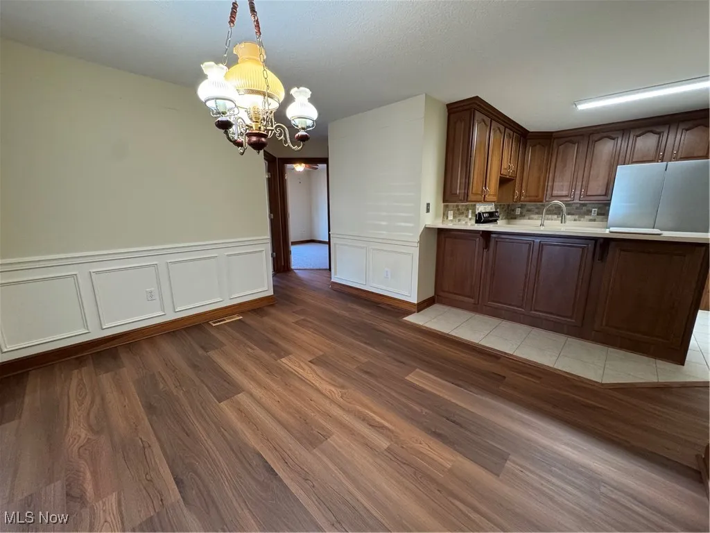 Kitchen featuring a chandelier, light countertops, light wood finished floors, hanging light fixtures, and a peninsula