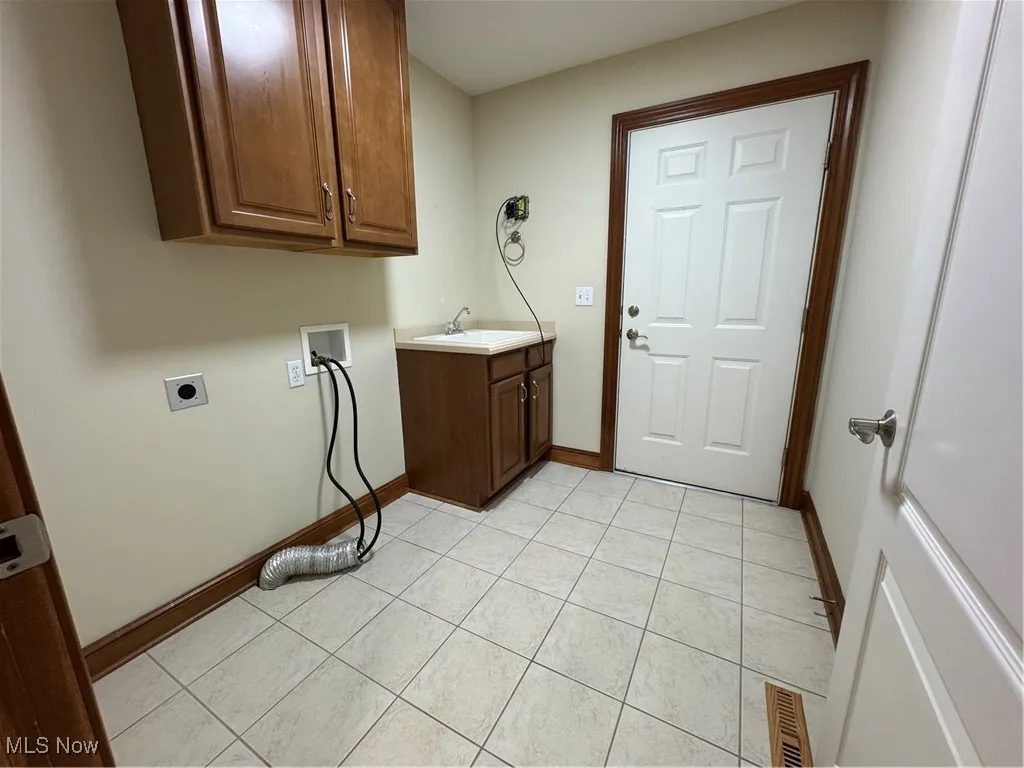 Laundry area with electric dryer hookup, cabinet space, washer hookup, and light tile patterned floors