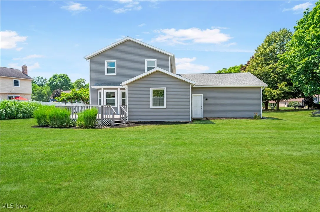 Rear view of house with a deck and a yard