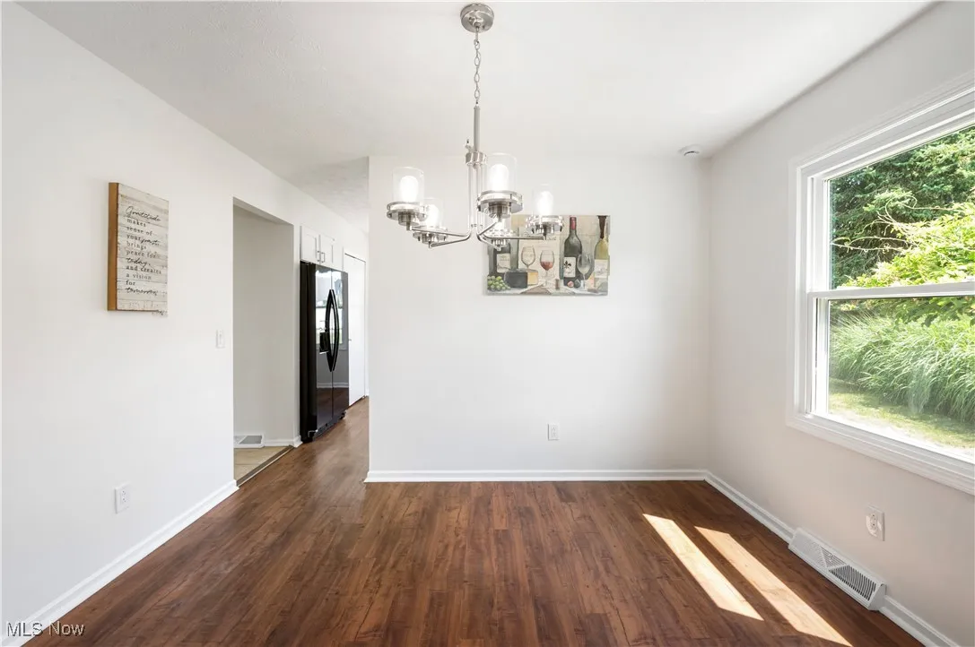 Spare room with a chandelier and dark wood-type flooring