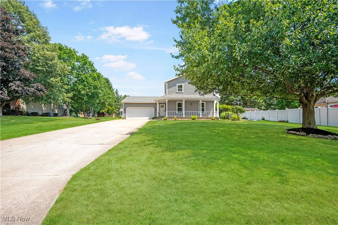 View of front facade with a porch, driveway, and an attached garage