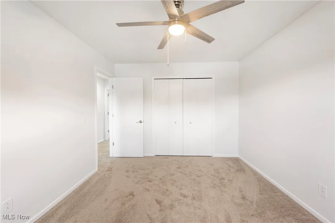 Unfurnished bedroom with carpet, a closet, and ceiling fan