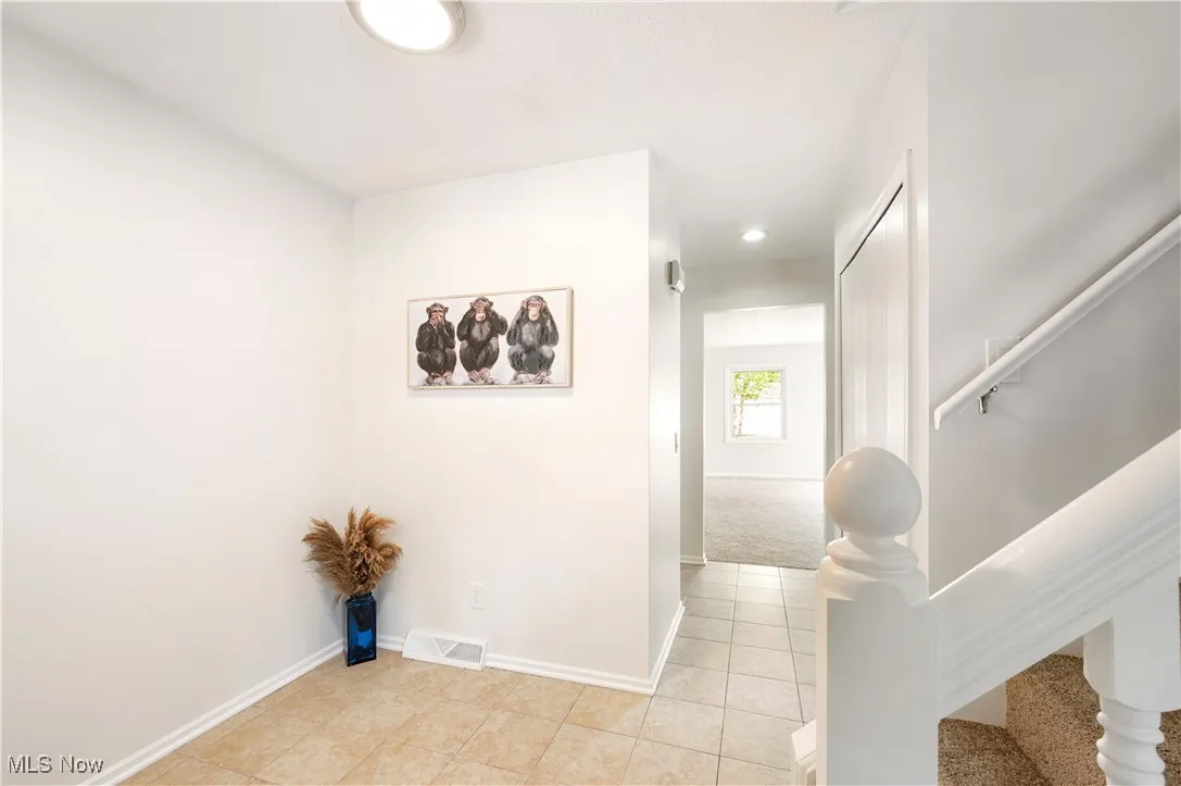Hallway featuring stairs, light tile patterned flooring, and recessed lighting