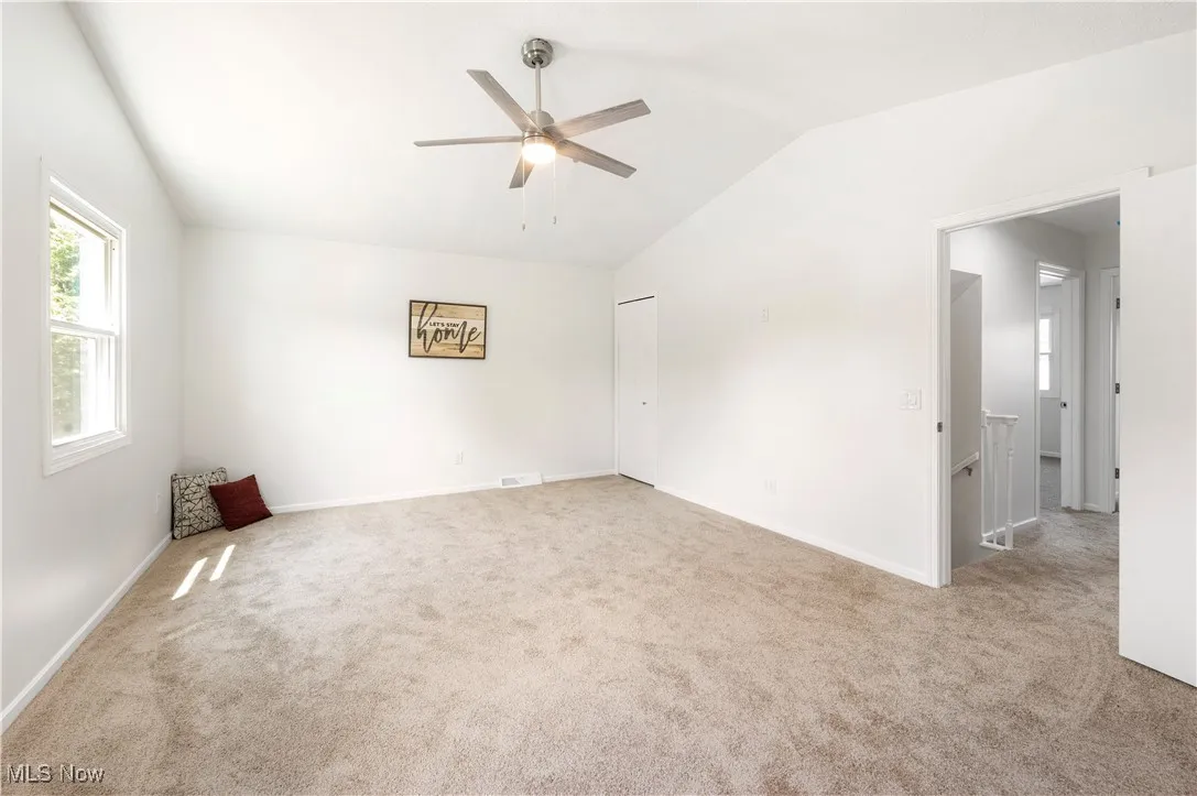 Unfurnished room featuring vaulted ceiling, carpet flooring, and ceiling fan
