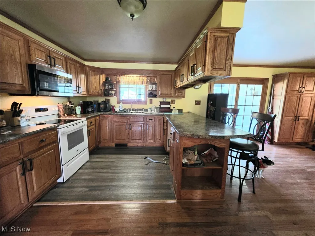 Kitchen featuring open shelves, range, stainless steel microwave, and dark countertops