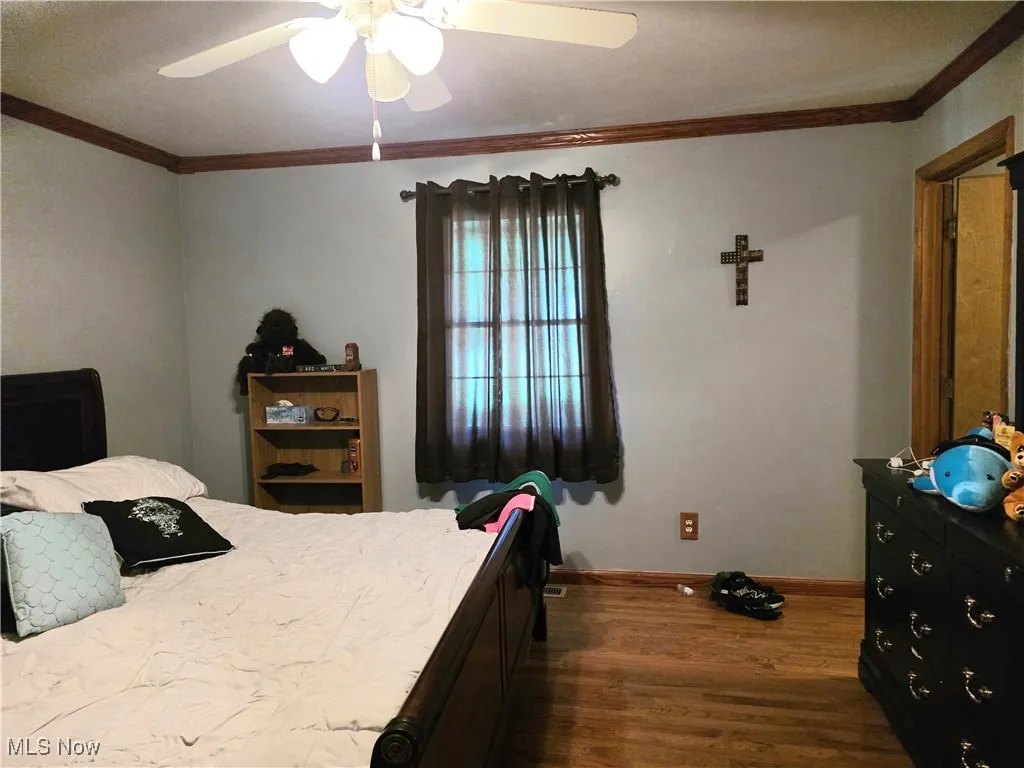 Bedroom with hardwood flooring, ornamental molding, and a ceiling fan