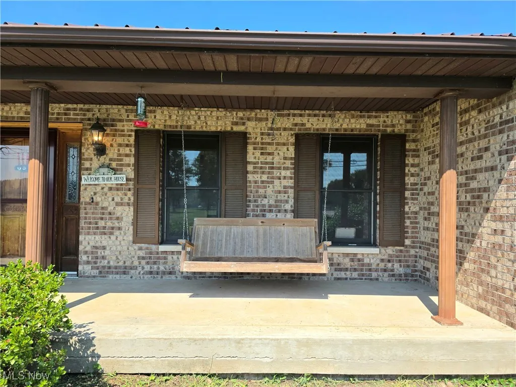 Entrance to property with brick siding and a porch