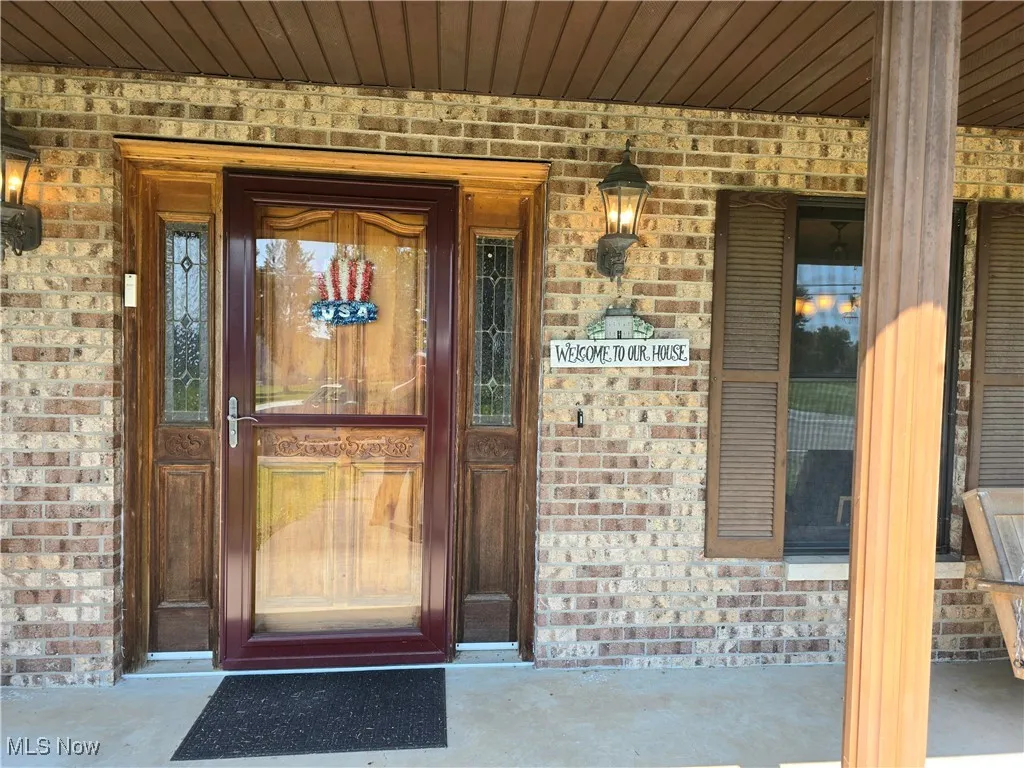 Doorway to property with brick siding and a porch