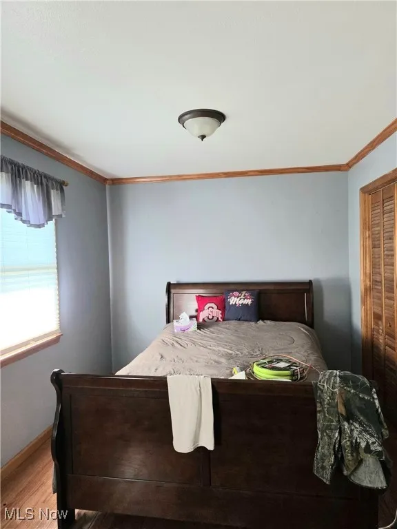 Bedroom with ornamental molding and light wood-type flooring
