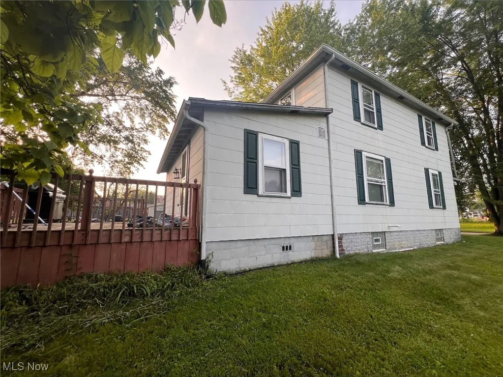 View of side of home with a deck, a lawn, and crawl space