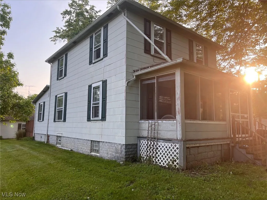 View of property exterior with a lawn, a sunroom, and entry steps