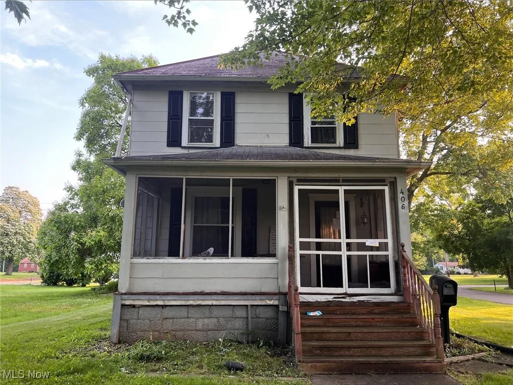 View of front of home with roof with shingles, a sunroom, and a front yard